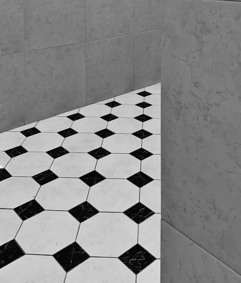A stylish black and white hexagonal tile pattern on a floor indoors, captured in grayscale.